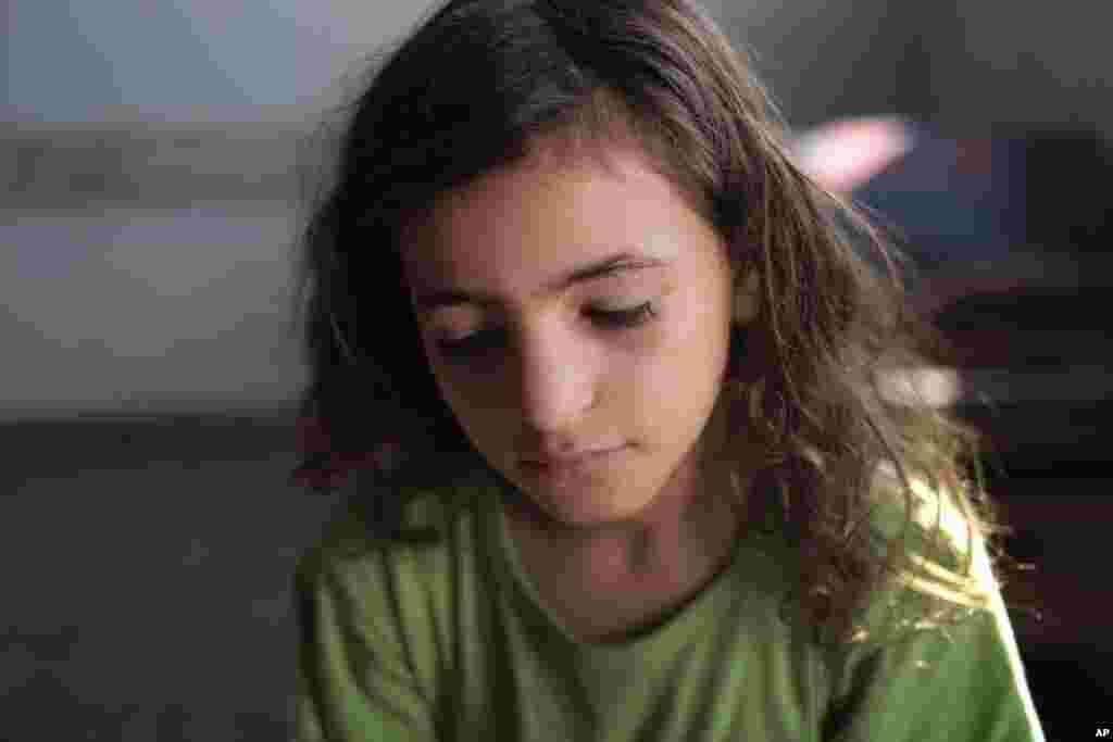 Bé gái người Palestine Yasmine Omar Al Attar, 10 tuổi, ngồi trong trường học của LHQ, nơi gia đình em đến lánh nạn tại thành phố Gaza, phía bắc Dải Gaza, ngày 6/8/2014.