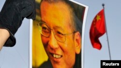 一位抗議者在中國駐奧斯陸大使館門外舉著劉曉波的照片。（資料圖片）