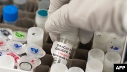 Seorang peneliti mengangkat botol vaksin Covid-19 di laboratorium Novavax di Gaithersburg, Maryland, salah satu laboratorium yang mengembangkan vaksin untuk virus corona. (Foto: AFP)