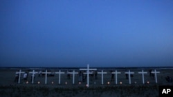 People gather near 11 crosses for the workers who died in the Deepwater Horizon oil rig explosion.