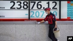 Un trabajador limpia el tablero electrónico de una firma de seguridad en Tokio el martes, 21 de enero de 2020.