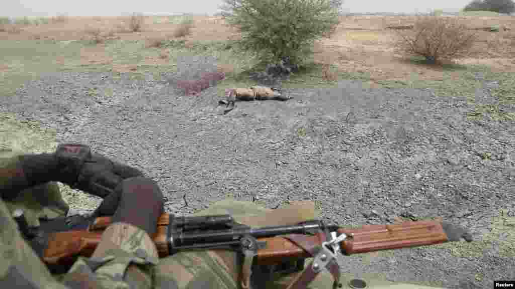 Des soldats tchadiens passent en voiture devant le corps d'un homme qu'ils disent être un combattant de Boko Haram tué par l'armée tchadienne au cours des combats à Gambaru, Nigeria, le 26 février 2015.
