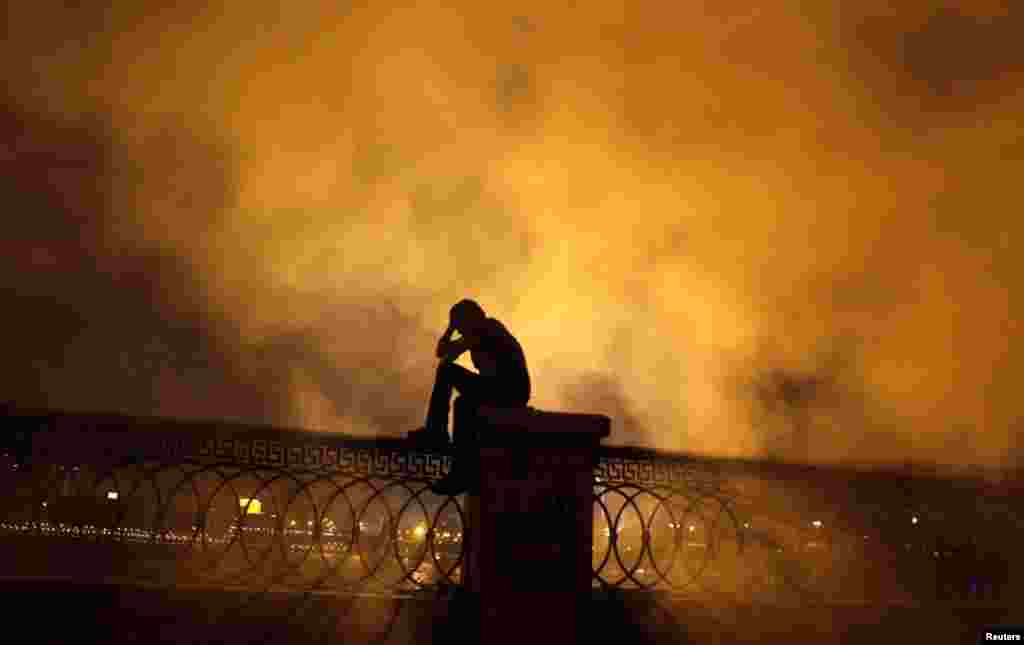 A protester covers his face in front of tear gas during clashes with riot police along a road at Kornish El Nile leading to the U.S. embassy, near Tahrir Square in Cairo, September 15, 2012.