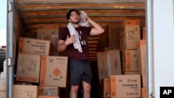 Ethan Hickman utiliza una toalla para secarse el sudor mientras se toma un descanso de descargar un contenedor bajo un calor sofocante, antes de la apertura de un puesto el lunes 17 de junio de 2024, en Weldon Spring, Missouri, Estados Unidos.