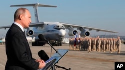 Presiden Vladimir Putin berpidato dihadapan pasukan Rusia di pangkalan udara Hemeimeem, di Suriah, 11 Desember 2017.