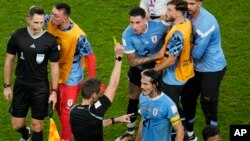 Jugadores uruguayos discuten con el árbitro alemán Daniel Siebert al final del partido de fútbol del grupo H de la Copa Mundial entre Ghana y Uruguay, en el estadio Al Janoub en Al Wakrah, Qatar, el viernes 2 de diciembre de 2022. (Foto AP/Aijaz Rahi )