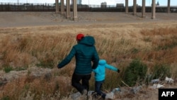Migrant iz Gvatamale sa sinom prelazi reku Rio Grande, prirodnu granicu između El Pasa u državi Teksas i Kjudad Huareza, u državi Čivava u Meksiku, u potrazi za političkim azilom, 26. januara 2021. (Photo by HERIKA MARTINEZ / AFP)