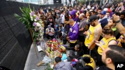 Fans of Kobe Bryant mourn at a memorial to him in front of Staples Center, home of the Los Angeles Lakers, after word of the Lakers star's death in a helicopter crash, in downtown Los Angeles, Jan. 26, 2020.