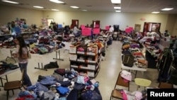 Migrantes detenidos tras cruzar ilegalmente a EE.UU. reciben alimentos y refugio en un albergue temporal de la Iglesia Católica Sagrado Corazón en McAllen, Texas, esperan orden de comparecer ante tribunales de inmigración. 27 de junio de 2014. 