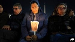 A woman holds a candle as Cardinal Robert Francis Prevost, Prefect of the Dicastery for Bishops, leads the recitation of the Holy Rosary for Pope Francis' health in St Peter's Square at the Vatican, March 3, 2025. 