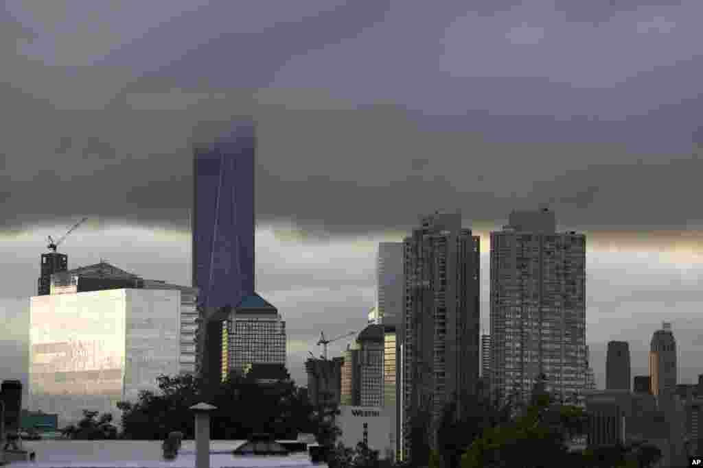 Low clouds surround the top of the One World Trade Center tower, center left, at sunrise during the 14th anniversary of the terrorist attacks, Sept. 11, 2015.