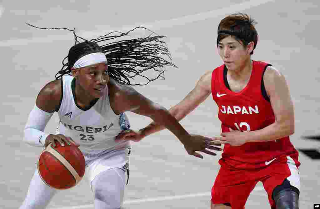 Nigeria's Ezinne Kalu (23) drives past Japan's Rui Machida (13), right, during women's basketball preliminary round game at the 2020 Summer Olympics, Monday, Aug. 2, 2021, in Saitama, Japan. (AP Photo/Charlie Neibergall)