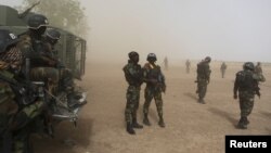 Les soldats camerounais de la Brigade d'intervention rapide, au milieu de la poussière lancée par un hélicoptère, patrouillent à Kolofata, au Cameroun, le 16 mars 2016.