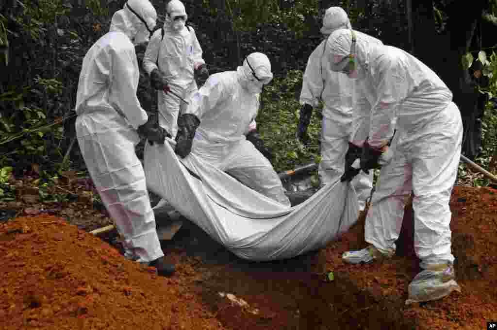 Des agents de service de santé enterrent la dépouille d'un malade d'Ebola mort au Liberia. (AP Photo/Abbas Dulleh)