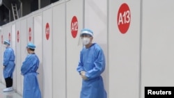 Miembros del personal esperan afuera de las casetas donde las personas reciben una vacuna contra el coronavirus (COVID-19) en un centro de vacunación, durante una visita organizada por el gobierno, en Beijing, China, el 15 de abril de 2021. REUTERS / Thomas Peter / File Foto
