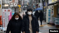 FILE - A couple wearing masks walks on a street during the COVID-19 pandemic in Seoul, South Korea, Dec. 13, 2020. The country saw a record number of marriages last year, possibly because weddings were delayed due to social restrictions during the pandemic. 
