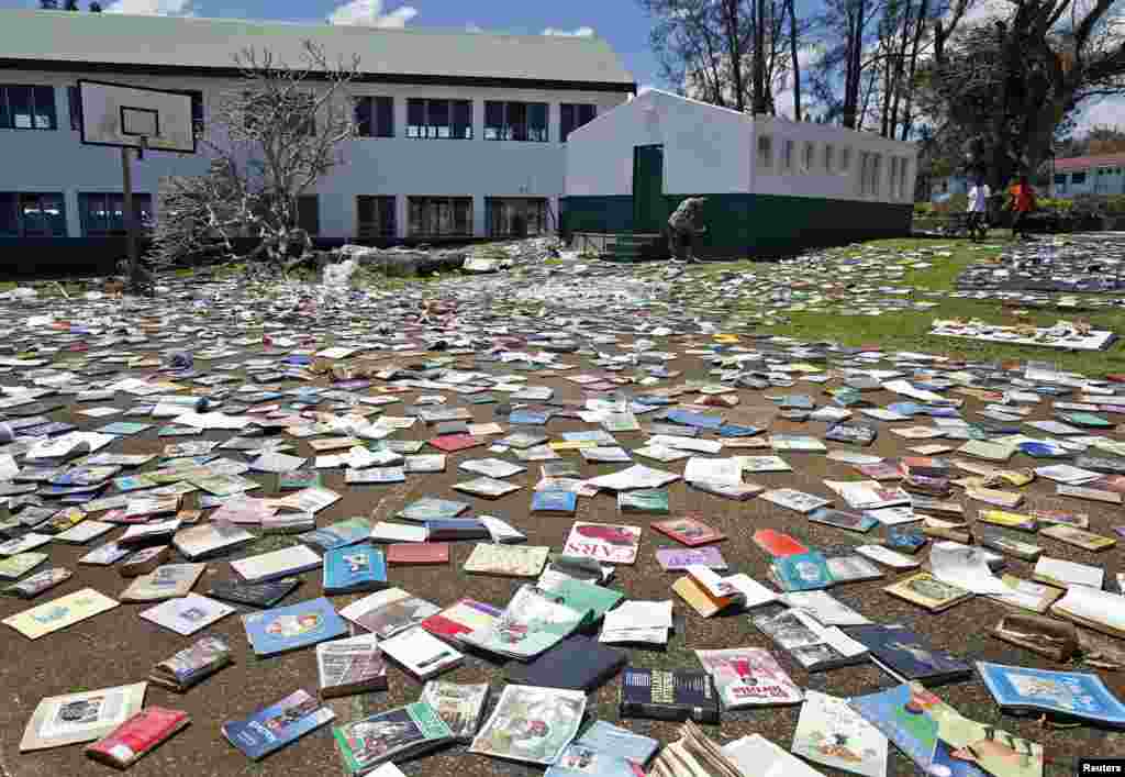 Paul Alexander Hatyay (tengah), kepala sekolah dan guru Central School, meletakkan buku-buku agar kering setelah atap perpustakaan sekolah tersebut ditiup oleh Siklon Pam di Port Vila, ibukota negara pulau Pasifik, Vanuatu. 