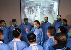 Chinese Premier Li Keqiang wearing a mask and protective suit speaks to medical workers as he visits the Jinyintan hospital where the patients of the new coronavirus are being treated in Wuhan, Hubei province, Jan. 27, 2020.