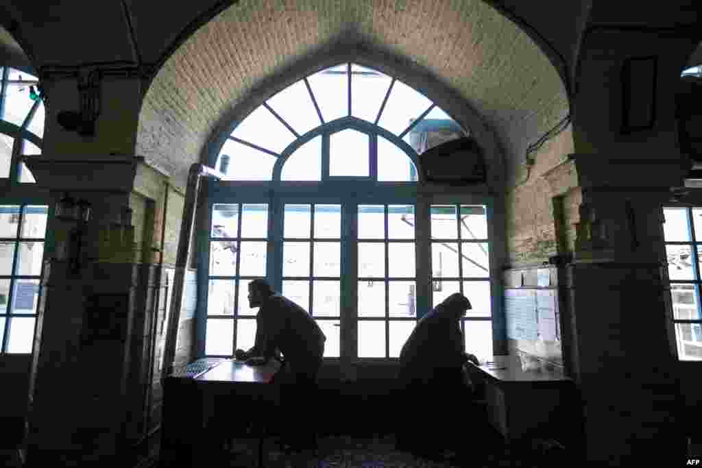 An Iranian man and a woman check the names of candidates from the list before voting for the parliamentary and Assembly of Experts elections at a polling station in the holy city of Qom, 130kms south of the capital Tehran, Feb. 26, 2016.