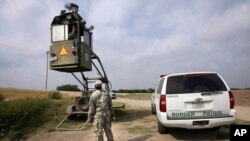 Un miembro de la Guardia Nacional supervisa a su colega dentro del palco de la Patrulla Fronteriza cerca del Puente Internacional Hidalgo en Hidalgo, Texas, el 19 de abril de 2011.