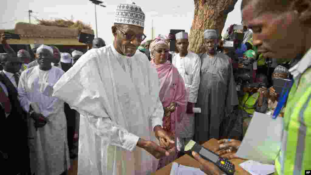Le candidat de l'opposition le général Muhammadu Buhari, au centre, arrive pour faire valider sa carte de vote à travers un lecteur d'empreintes digitales, avant de revenir voter plus tard dans la journée, dans sa ville natale de Daura, Nigeria Saturday, samedi 28 mars 2015.