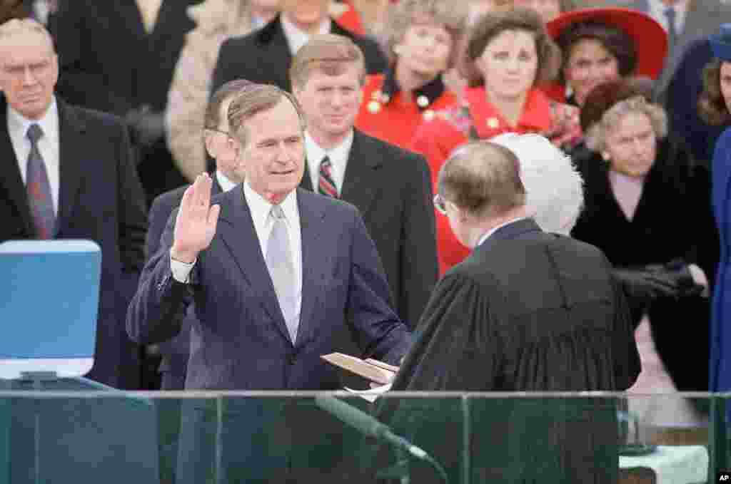 George H. W. Bush levanta la mano mientras toma el juramento de su cargo como presidente número 41 de Estados Unidos, el 20 de enero de 1989.