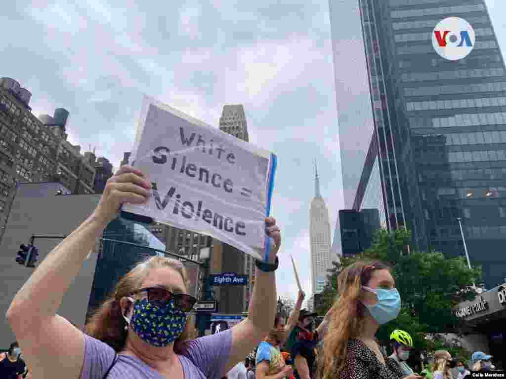 Una manifestante sostiene un cartel que se traduce: "Si el blanco calla es igual a violencia". Foto: Celia Mendoza-VOA