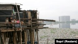 Anak-anak berdiri di dalam rumahnya di atas danau yang tercemar sampah di kawasan kumuh, Jakarta Utara. (Foto: REUTERS/Supri)