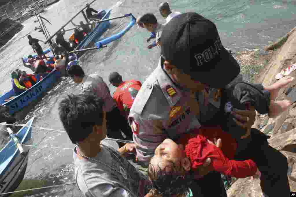 A police officer carries a child who appears to be unconscious after a boat carrying asylum seekers sank off West Java, Indonesia, July 24, 2013. 