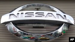FILE - Vehicles are reflected on the logo of the Nissan Motors Co. at a showroom in Tokyo's Ginza shopping district, Japan.
