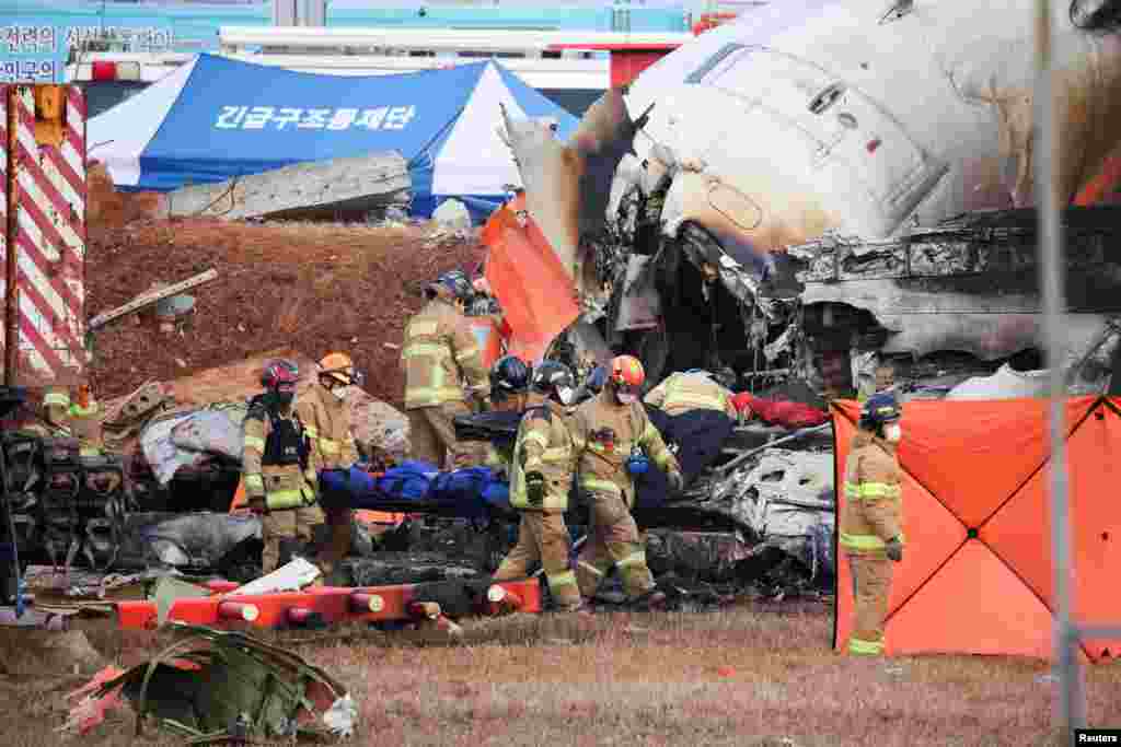 Firefighters carry the body of a passenger from the wreckage of a Jeju aircraft that crashed after it went off the runway at Muan International Airport, in Muan, South Korea, Dec. 29, 2024.