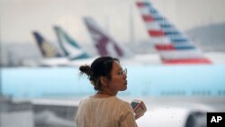 Une femme se tient debout avec son téléphone portable à l'aéroport international de Hong Kong, le lundi 12 août 2019. 
