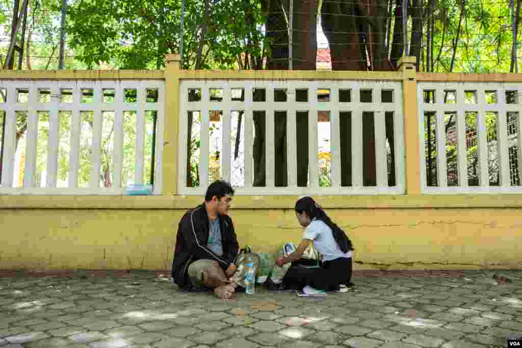 លោក ម៉ៅ សុភាព ដែលជាឪពុករបស់បេក្ខជនប្រឡង ម៉ៅ ម៉ាឡែន មកពីវិទ្យាល័យឫស្សីកែវ បង្ហាញការលើកទឹកចិត្តដល់កូនស្រីដែលត្រូវប្រឡង ដោយដាក់ច្បាប់ឈប់សម្រាកការងាររយៈពេលពីរថ្ងៃ ដើម្បីធ្វើម្ហូបអាហារយកឲ្យកូនស្រីរបស់លោក នៅមណ្ឌលប្រឡងវិទ្យាល័យព្រះស៊ីសុវត្ថិ នៅថ្ងៃទីពីរ នៃការប្រឡងសញ្ញាបត្រមធ្យមសិក្សាទុតិយភូមិ កាលពីរសៀលថ្ងៃទី២០ ខែសីហា ឆ្នាំ២០១៩។ (ប៊ុន សុខា/VOA)