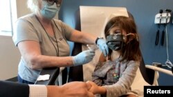 FILE - Bridgette Melo, 5, holds the hand of her father, Jim Melo, during her inoculation of one of two reduced 10 ug doses of the Pfizer BioNtech COVID-19 vaccine during a trial at Duke University in Durham, North Carolina, Sept. 28, 2021.