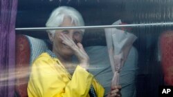 A passenger waves from a bus after she disembarked from the MS Westerdam, owned by Holland America Line, at the port of Sihanoukville, Cambodia, Friday, Feb. 14, 2020. Passengers finally disembarked on Friday from the cruise ship allowed to dock in…