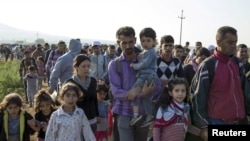 Migrants walk along a road in the village of Miratovac near the town of Presevo, Serbia, Aug. 25, 2015. 