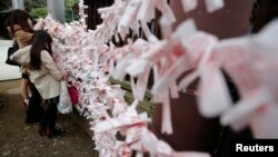 Sepasang kekasih berjemur sambil berbaring di rumput, di belakang sebuah patung di Odaiba Seaside Park di Tokyo, Jepang. Suhu meningkat hingga 35 derajat Celsius.