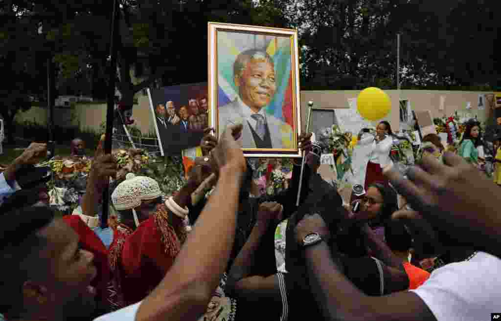 As pessoas cantam à porta da casa de Nelson Mandela em Joanesburgo, Dez. 9, 2013.