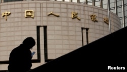 資料照：一名男子坐在中國人民銀行總部大樓外。