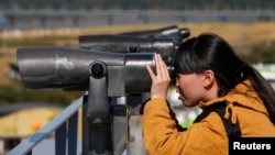 一位中國遊客在北韓境內分隔南北韓的非軍事區附近的臨津閣用望遠鏡向北觀望。（2013年10月16號）