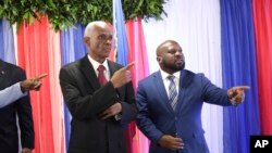 Edgard Leblanc Fils, a la izquierda, y Smith Augustin se preparan para una foto de grupo con el consejo de transición después de que Fils fuera nombrado presidente del organismo. En Puerto Príncipe, Haití, el martes 30 de abril de 2024. 