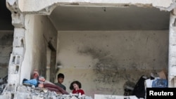 Anak-anak Palestina tampak berada di sebuah rumah yang telah hancur akibat serangan Israel, di Rafah, Jalur Gaza, pada 22 Mei 2024. (Foto: Reuters/Hatem Khaled)