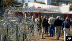 Una cerca de alambre de púas se erige a un costado de un camino de tierra por el que avanzan legisladores cerca de la frontera entre Texas y México, el 3 de enero de 2024, en Eagle Pass, Texas. 