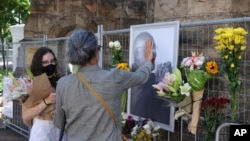 Des gens déposent des fleurs à côté d'une photo de l'archevêque anglican Desmond Tutu à la cathédrale Saint-Georges du Cap, en Afrique du Sud, le 26 décembre 2021.