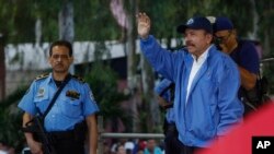 Escorté par un de ses gardes de sécurité armés, le président nicaraguayen Daniel Ortega, à droite, à Managua, au Nicaragua, le samedi 7 juillet 2018. (AP Photo / Alfredo Zuniga)