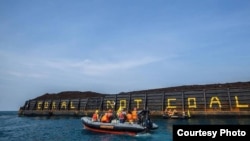 Aktivis Greenpeace menulis "Coral not Coal" di lambung tongkang batubara di Karimunjawa. (Foto: Greenpeace Indonesia).
