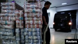 Seorang pedagang bersiap mengangkut uang ke dalam kendaraan di kantor Bank Mandiri di Jakarta. (Foto: Dok)