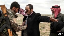 Para pria yang dicurigai anggota kelompok militan ISIS sedang diperiksa oleh anggota Pasukan Demokratik Suriah (SDF) yang dipimpin oleh Kurdi, setelah meninggalkan wilayah pertahanan terakhir ISIS, Baghuz, di Provinsi Deir Ezzor, 27 Februari 2019.
