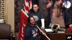 En esta imagen de archivo del video de la Policía del Capitolio, Paul Allard Hodgkins, de 38 años, de Tampa, Florida, al frente, está parado en el piso del Senado, el 6 de enero de 2021, en Washington DC.