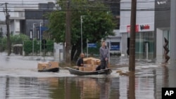 Voluntarios transportan suministros donados en un bote a través de una calle inundada después de fuertes lluvias en Porto Alegre, estado de Rio Grande do Sul, Brasil, el domingo 12 de mayo de 2024.